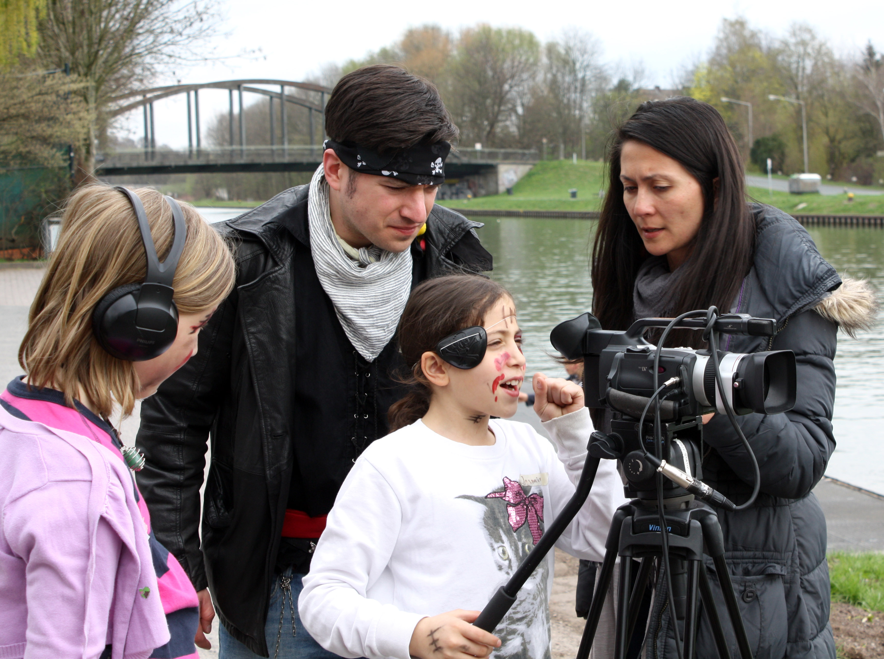 Zwei Medientrainer und zwei Kinder arbeiten mit einer Kamera