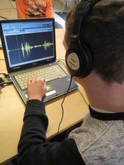 Junge mit Kopfhörer (Hinteransicht) bedient Schnittprogramm am Laptop