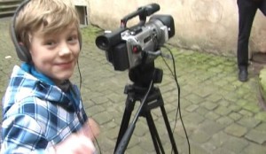 Junge vor Videokamera, lächelndes Gesicht zum Betrachter.