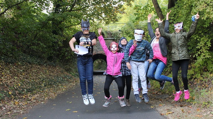 Junge Menschen springen in die Luft, einige haben Masken auf