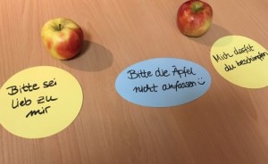 Zwei Äpfel, drei Zeittel mit der Aufschriften: Bitte sei lieb zu mir, Bitte nicht anfassen, Mich darfst du beschimpfen