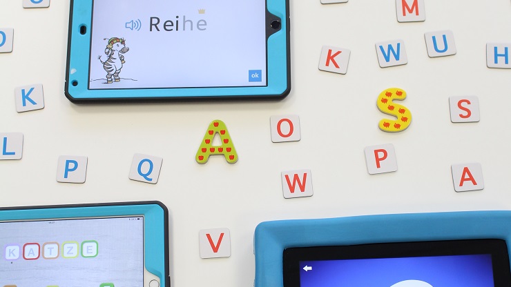 Tablets mit Lese-Apps vor weißem Hintergrund mit bunten Buchstaben