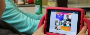 Junge hält iPad in pinker iPad-Halterung in der Hand, zu sehen ist ein Comic auf dem Bildschirm