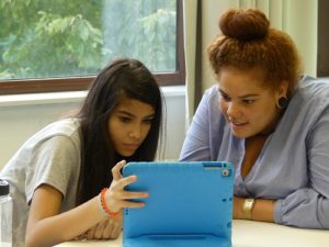 Melanie Leusch von der Inklusiven OT Ohmstraße zeigt einem Mädchen etwas auf einem iPad mit blauer Hülle