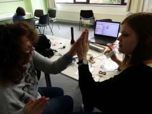 Junge Frau und Mädchen geben sich High-Five, während die eine die MaKey MaKey-Platine in den Händen hält