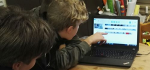 Kinder vor Laptop, ein Junge zeigt auf etwas