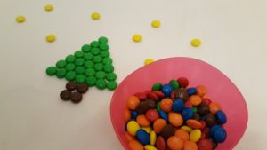 Schüssel mit Smarties, daneben ein aus Smarties gelegter Weihnachtsbaum mit Sternenhimmel