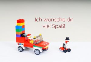 Weihnachtspostkarte. Motiv: ein Weihnachtsmann in einem Weihnachtsmobil aus LEGO. Aufschrift: Ich wünsche dir viel Spaß