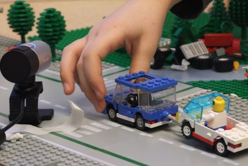 Kinderhand bewegt Lego-Auto vor Kamera