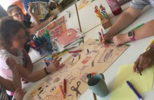 Kinder mit Mal- und Bastelutensilien gestalten Plakate