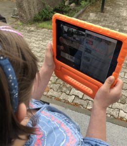 Mädchen filmt mit iPad in orangener Schutzhülle