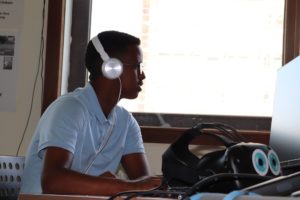 Junge mit Kopfhörer auf am Computerarbeitsplatz