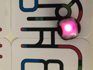 Pink blinkender Ozobot fährt auf Bahn, die aus Karten gelegt wurde