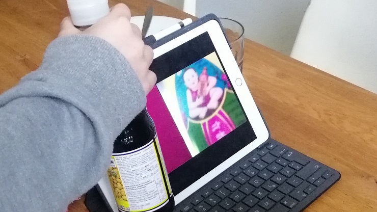 Kind hält Sojasoßenflasche vor Tablet-Kamera