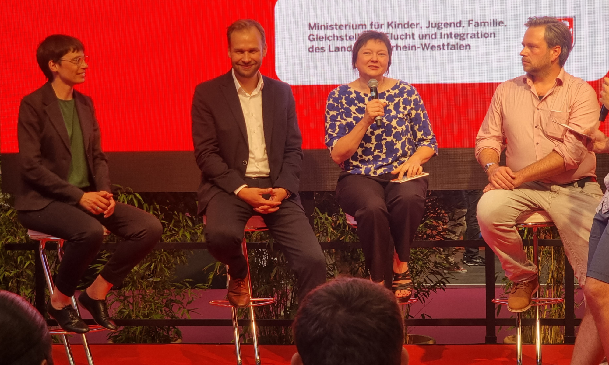 v.l.n.r.: Ministerin Josefine Paul, Robert Voigtsberger, Beigeordneter für Bildung, Jugend und Sport der Stadt Köln, Dr. Christine Ketzer von der LAG LM und Markus Sindermann von der FJMK auf der Bühne des Jugendforums NRW 2022