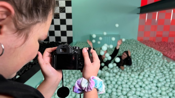 Jugendliche fotografiert andere Jugendliche im Bällebad, die Bälle sehen aus wie Zuckerkügelchen