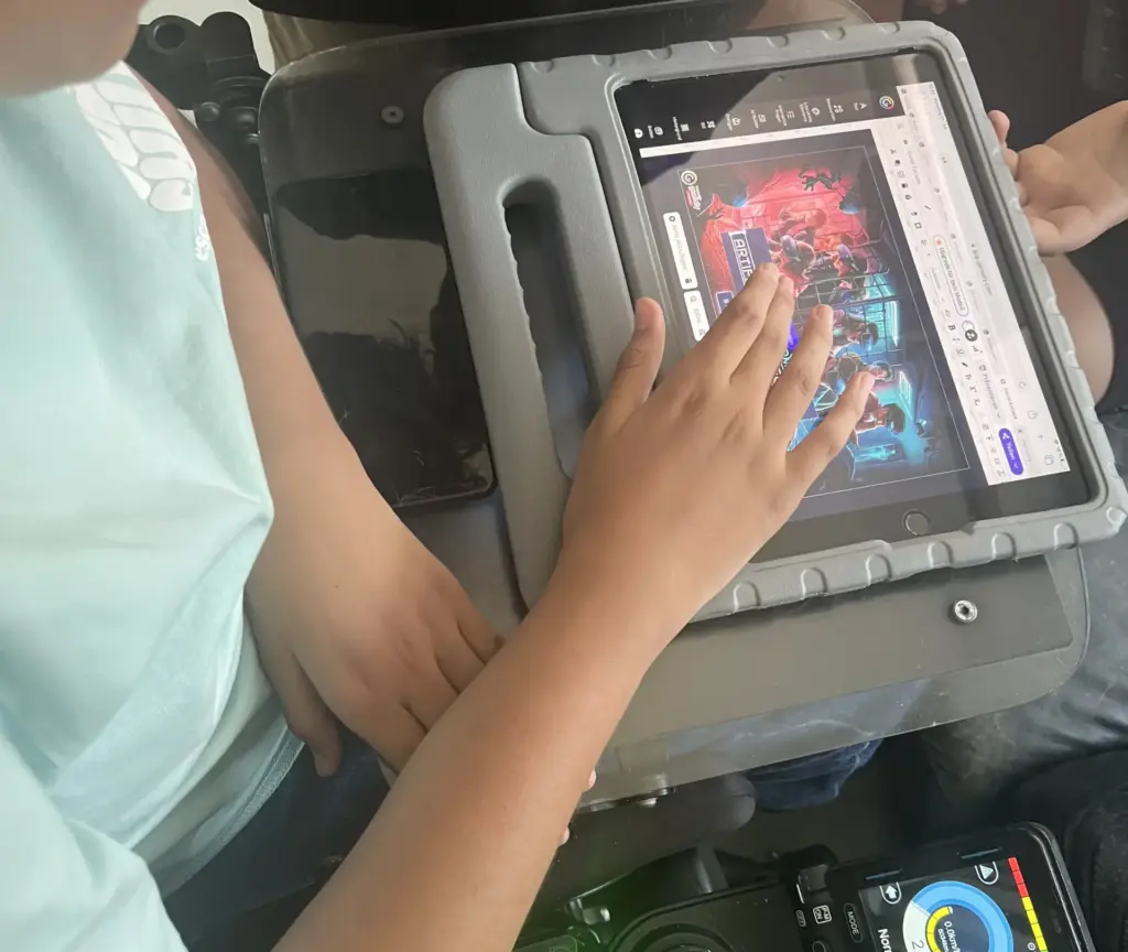 Kind im Rollstuhl bedient mit der rechten Hand ein Tablet mit Escape-Room-Spiel, das auf einem Rollstuhl-Tablett befestigt ist.